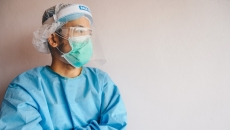 Person in PPE rests against wall