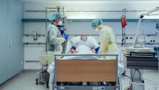 Clinicians gather around a COVID patient in a hospital bed