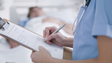 A person in medical wear holds a paper document on a clipboard