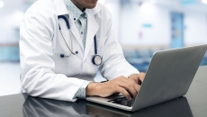 A person wearing a stethoscope on a computer