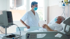 A COVID-19 patient speaks to a doctor, both in masks