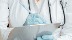 Person in PPE writes on clipboard