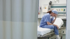 Nurse holding head in hands sitting on a hospital bed
