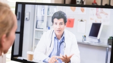 A patient having a virtual consultation with a doctor on a desktop computer