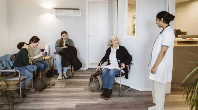 Nurse calls for a patient in a waiting room Nurse calls for a patient in a waiting room