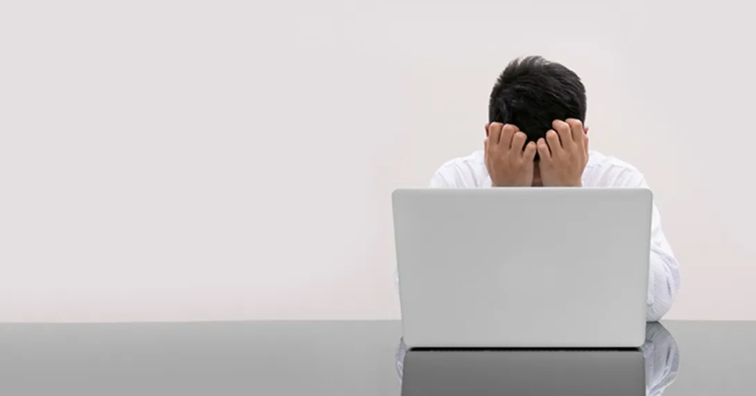 A doctor with their head in their hands in front of a computer