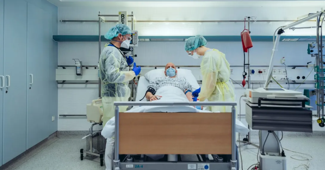 Clinicians gather around a COVID patient in a hospital bed