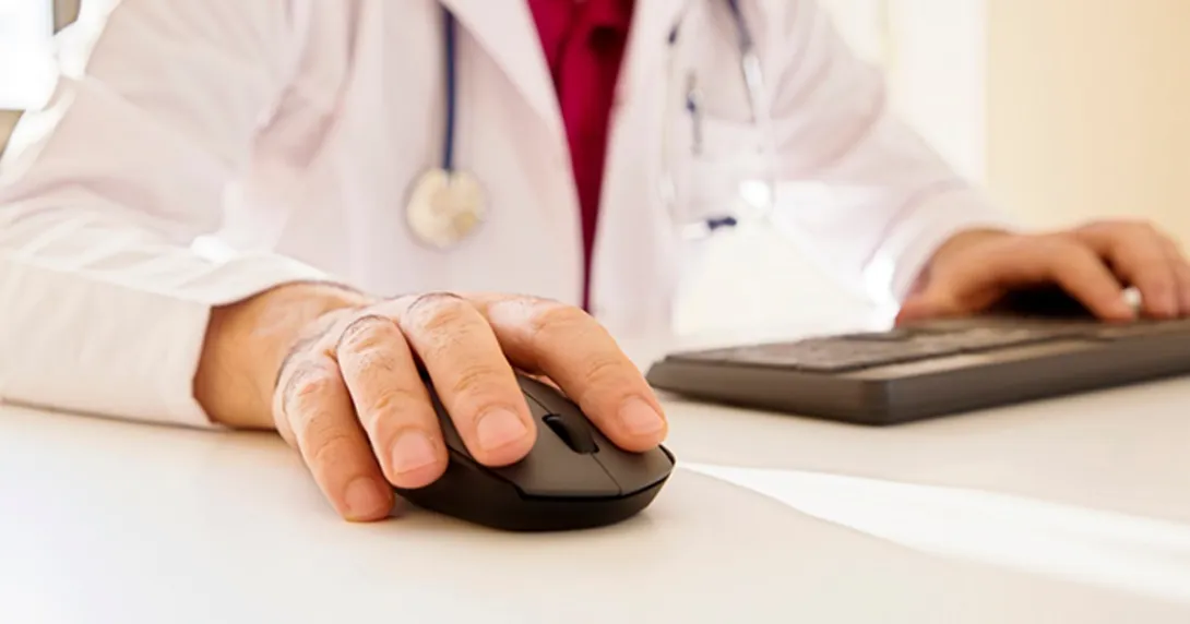 Person in white jacket operates keyboard and mouse