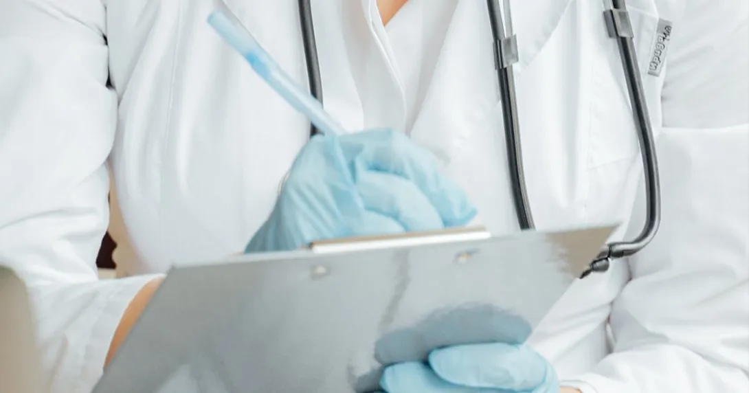 Person in PPE writes on clipboard