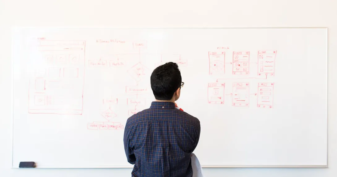 Developer faces a whiteboard looking at a tech stack diagram Developer faces a whiteboard looking at a tech stack diagram